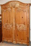 Lot# 112 CARVED PINE ARMOIRE, H 82", W 56", D 26", bleached pine armoire, having a carved crest with doves; two full height cabinet doors opening to two shelves above three open drawers; contoured carved skirt and contoured carved legs.
