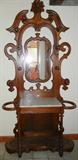 Lot# 147 ANTIQUE AMERICAN MAHOGANY & MARBLE COAT & UMBRELLA STAND, H 8', L 45", Leaf & grape design at crest with central mirror with pierced design and contoured framework with turned spindle coat and hat hangers; inset white/grey veined marble top separates two umbrella stands, all supported by turned spindle legs with contoured skirt at bottom of lower shelf;
