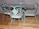 Lot# 175 WIDDICOMB, PATIO TABLE AND CHAIRS, CAST IRON AND BENT METAL, 5 PCS., includes a rectangular glass top patio table with a scroll form cast iron pedestal frame with four legs and sheet metal leaf accents, 28" H. x 50" W. x 30" D; four chairs of bent metal with fruit basket back splats and rose pattern removable cushions.