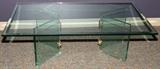 Lot# 245 BEVELED GLASS COFFEE TABLE, H 15", W 30", L 48", having a beveled glass edge to the top with two opposing 'V' shape pedestals assembled with brass brackets all supporting the top.