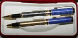 Lot# 301 CHARLES G STEWART, PEN AND PENCIL SET IN CASE, includes a ballpoint pen and a mechanical pencil; swirl design with blue enamel on cap. Gilt metal pocket clip; includes red velvet fitted case;