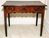 Lot# 1028 WALNUT THREE-DRAWER TABLE, 19TH C., H 29", W 33", D 18 1/2", Rectangular top with beveled edge above three drawers and a scalloped apron, raised on square tapering supports. From the Estate of Walter Connolly, Grosse Pointe Farms, Mi.
