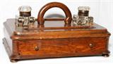 Lot# 1101 VICTORIAN OAK INKSTAND, LATE 19TH C., H 7", W 14", Rectangular form with rounded corners, centered by a loop handle flanked by two glass ink bottles, above a single drawer, raised on four feet. From the Estate of Walter Connolly, Grosse Pointe Farms, Mi.