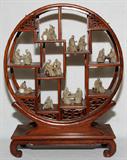 Lot# 1175 CHINESE MUD FIGURES, COLLECTION OF 13, H 2" ON WOOD STAND, Collection of 13 various figures, H.2" each approximately, arranged within a round rosewood, staggered tier stand fitted with eleven shelves, H.19", W.14". From the Collection of John P. O'Hara, Bloomfield Hills, Mich.