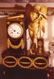 178/99  Clock.  A 19th century French circular clock outlined in ormolu and showing ormolu mounts as anthemia at the upper corners of the case and a swag beneath the clock face.  A bow and quiver of arrows rests atop the clock casing.  A gilt bronze figure of an angel rests upon an anchor set on an ormolu mounted stand.  All the above are on a footed matching base diplaying ormolu mounts.
The porcelain face is cracked.
13" wide x 4 1/2" deep x 19 1/4" high
As is:  $2250.00