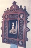 269/212  Picture.  A 19th/20th century Middle Eastern pietra dura [hard stone] picture of a woman standing in front of a building.  
In an ebonized walnut inner frame with description in Arabic.
This in an ornate carved and pierced walnut and inlaid ivory outer frame measuring 13 3/4" x 18 1/2" overall.  $575.00