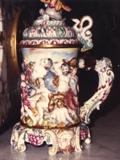 167/230  Stein.  A 19th century Italian Capodimonte stein displaying a battle scene overall in relief.  A snake form thumb lift.  The lid with a helmet finial.  Fancy handle with winged head.  The base of heads and grapes.
9 1/2" high.  $675.00