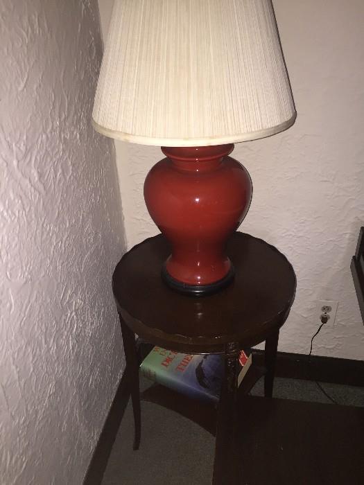 RED LAMP ATOP OF ROUND MAHOGANY TABLE