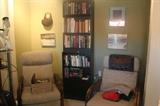 Two matching push back recliners , three black bookcases, assortment of books.