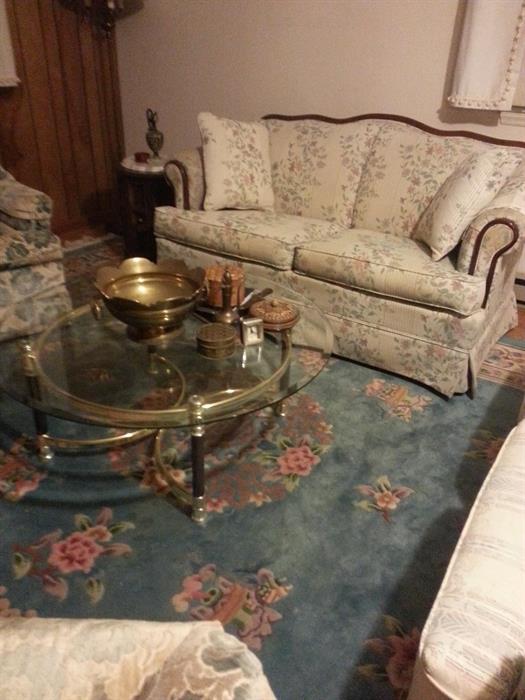 Floral loveseat and cherry trim and round glasstop & brass coffee table.