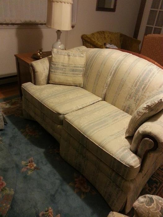 Striped loveseat with maple wood trim.
