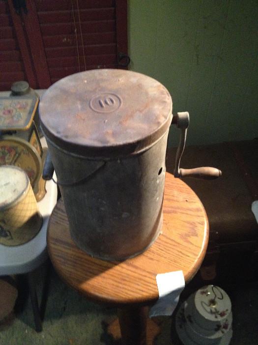 Antique ice cream maker shows andle and hole for salted ice water to escape