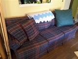 Plaid couch with pillows, blue white crocheted blanket.