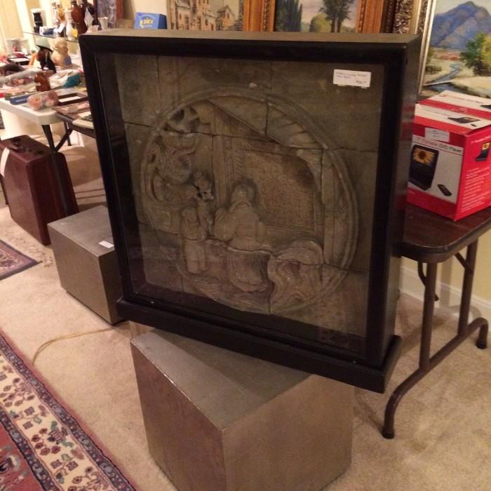 Framed stone Asian temple wall fragment sitting on 1 of 3 metal veneered "bunching" tables