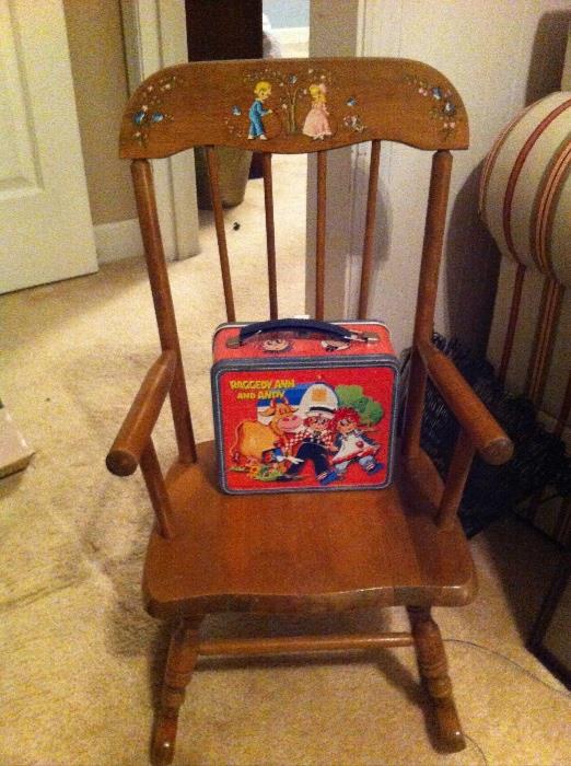 Child's rocking chair with Raggedy Ann and Andy lunch box and thermos.