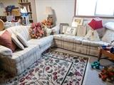 Stylish sofa and love seat with pillows. Large area rug that shows little sign of wear