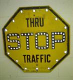 Vintage 1930s yellow stop sign with cats' eyes.