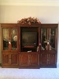 Three unit entertainment center;TV; knick knacks; floral arrangements;