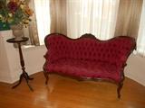 Dining Room: A fern stand is to the left of a beautiful deep rose VICTORIAN 54" tufted settee. The settee was originally purchased at Geronimo's Cadillac in the Central West End (a copy of the original price tag is included).