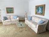 Living room couch, matching loveseat, brass and glass end tables and coffee table (artwork not for sale).