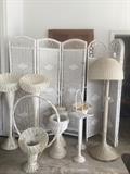 Several white wicker flower baskets, vases, lamps, room dividers, and more