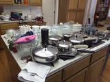 Collection of pots and pans, small, medium, large sized pots and pans, glass serving bowls and dishes, variety of kitchen ware.