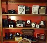 Nikon FE with 50mm lens; slide viewers; Poloroid Land Cameras; Kodak Brownies; movie cameras; light meters