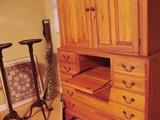 View of pine cabinet with small drop front writing surface. Pair of antique candle stands in background