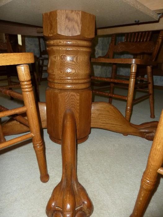 Solid oak table with claw foot pedestal and 6 wood carved press back chairs