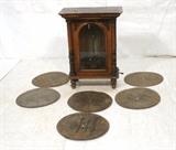 Lot 57:  POLYPHON Elaborate Music Cabinet. Six Metal disc records. Penny slot. Nicole Freres Ltd. Fabricants. Carved Column front Cabinet. with arched glass door. Marked. See photos. Records include "La Belle Polonaise" Mazurka. Torganauer March". "Der Tannenbaum" Christmas song. . etc.  etc. : Dimensions:  H: 37 inches: W: 27.5 inches: D: 15.5 inches --- 