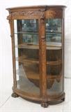 Lot 79:  Large Carved Oak Bow Front. Well carved with lions head & paw feet. Bowed front & side glass. Shaped wood interior shelves. : Dimensions:  H: 71 inches: W: 49 inches: D: 24 inches --- 