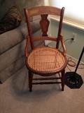  Cane bottomed chair. Base of floor lamp also seen.