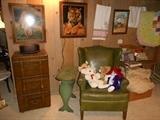 Lower Level:  A file cabinet that looks like stacked luggage; vintage green stenciled book/reading table; green wingback chair; prints; stuffed animals; linens.