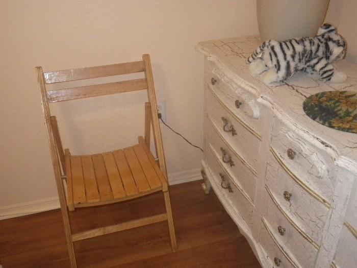 Folding chair and distressed dresser with a cut little white tiger