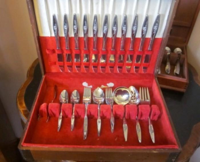 Two sets of stainless flatware in storage boxes.