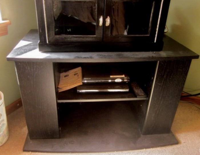 Glass door tabletop storage cabinet and black TV stand.