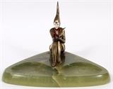Lot#1115, ART DECO STYLE SPELTER FIGURE MOUNTED ON ONYX, C. 1940, H 8", W 11"J. B. Hirsch figure of patinated harlequin or pixie girl reading book. Made of spelter ("French bronze") and celluloid. H 7 3/4"; W 11 1/2". Circa 1940.