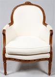 Lot#1366, LOUIS XVI STYLE ARMCHAIR, C. 1920,,Upholstered with loose seat cushion. Hand carved walnut frame. Circa 1920. Serpentine seat rail. Carved leafy arm terminals, bow knot carved crest.  Made in France. From the collection of Dr. Marion Scott and Ann Scott, Grosse Pointe Shores.
