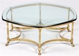 Lot#122, BRASS & GLASS COCKTAIL TABLE, H 14 1/2", DIA 41"Having a hexagonal-shaped thick glass top with a brass frame having six legs with curved stretchers and hoof feet.