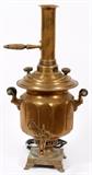 Lot#146, RUSSIAN BRASS SAMOVAR, DATED 1898, H 25", W 13", D 13"Russian brass samovar having a brass chimney with turned wood handle, attached to a round lid with two turned wood handles. Faceted sided body with two handles with turned wood grips. Scrollwork spigot on spout. Square footed base stamped with Cyrillic seals and inscriptions in Russian. Electrified.