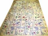 Lot#215, INDIAN DHURRIE, HAND WOVEN WOOL RUG, W 8' 11", L 11' 5"Having a cream ground, with a shadowbox motif populated with multi-colored flowers. Signed at the edge (see secondary photo). No borders.