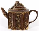 Lot#232, CHINESE BRONZE TEAPOT, H 4", W 5"Having an elongated octagonal shape decorated with a foo dog finial on the lid above figures on the sides including a sage and animated figures all in high relief. Depress leaf mark on the underside.