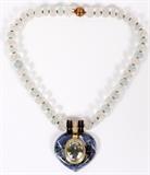 Lot#2061, DAVID WEBB 18KT YELLOW GOLD, SODALITE, TOPAZ, DIAMOND & CRYSTAL QUARTZ, TOPAZ NECKLACE,,Necklace contains one oval shape faceted topaz weighing approximately 18 carats with measurements of approximately 19mm long x 15mm wide x 9.25mm depth. Grades of color listed as high intensity light blue. Color evenness is even. Clarity is free of inclusions. Transparency is transparent. Cut and polish are good and bezel set. There are fifty nine full cut round diamonds weighing approximately 0.015 carat each. Grades of clarity VVS-1 to VS-2. Color grade is H to I. Cutting grade is very good and mounted flush. One hearts shape polish sodalite measuring approximately 42mm x 38mm. Grades of color light to medium/dark blue mottled with white veins. Transparency opaque. Cut and polish are good. Frosted carved crystal quartz beads measuring 9mm diameter. Yellow gold split ring spacers. Blue enameling. The necklace measures approximately 15" long. Stamped "D.WEBB" and weighs 106.3 grams.
