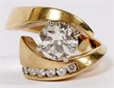 Lot#2161, 1.78CT DIAMOND AND 14KT YELLOW GOLD LADY'S FREE FORM RING.Ladies free form style ring, by-pass design. Contains one center round brilliant cut diamond, weighing approximately 1.78ct. Color H, clarity I1. On one side of the by-pass is one row of channel set containing six round brilliant cut diamonds, weighing approximately 0.25cttw. Color H, clarity SI2. The ring is currently size 8 and weighs 10.7 grams.