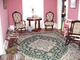 View of upstairs parlor with Oriental rug, two Victorian chairs, and Victorian marble top console table with Victorian lamp