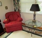 Red lounge chair in office, glass top metal base side table, and black marble base lamp