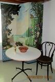 Cafe table shown in front of 3 panel folding painted screen ( Welcome to Venice ?)