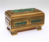 Lot# 1016 A French malachite and onyx-inlaid gilt bronze jewelry casket, Tahan 









Second half 19th century, stamped to lock plate ''Tahan. R. De La Paix'', the hinged rectangular top decorated with Greek key borders surrounding a panels inlaid with stylized foliate motif, opening to a well lined with cream colored silk, over a conforming base. 3.5'' H x 6.5'' W x 3.75'' D. est:$700/900