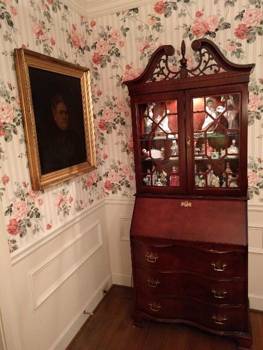 Lighted china cabinet, by Jasper Cabinet, Co, Jasper, IN.                                                                                           The poor soul depicted in the Rembrandt style portrait, was great Aunt Hulga, who was a charwoman and mainly lived in the basement, hence her charming personality so gleefully depicted in oil. 