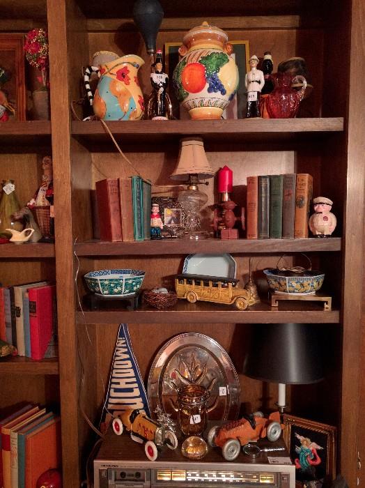 Fun-filled bookcase in the den, with cast iron toy collection, old books, porcelain goodies.